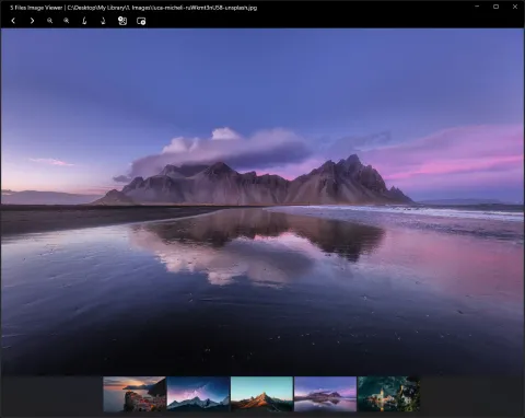 The image viewer showing a mountain reflected on a wet beach at dusk, with toolbar buttons for previous, next, zoom and rotate, and a strip of thumbnails of the other photos in the folder